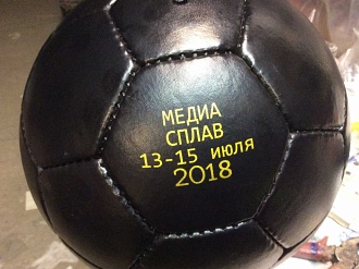 Логотип золотого цвета на футбольном мяче.